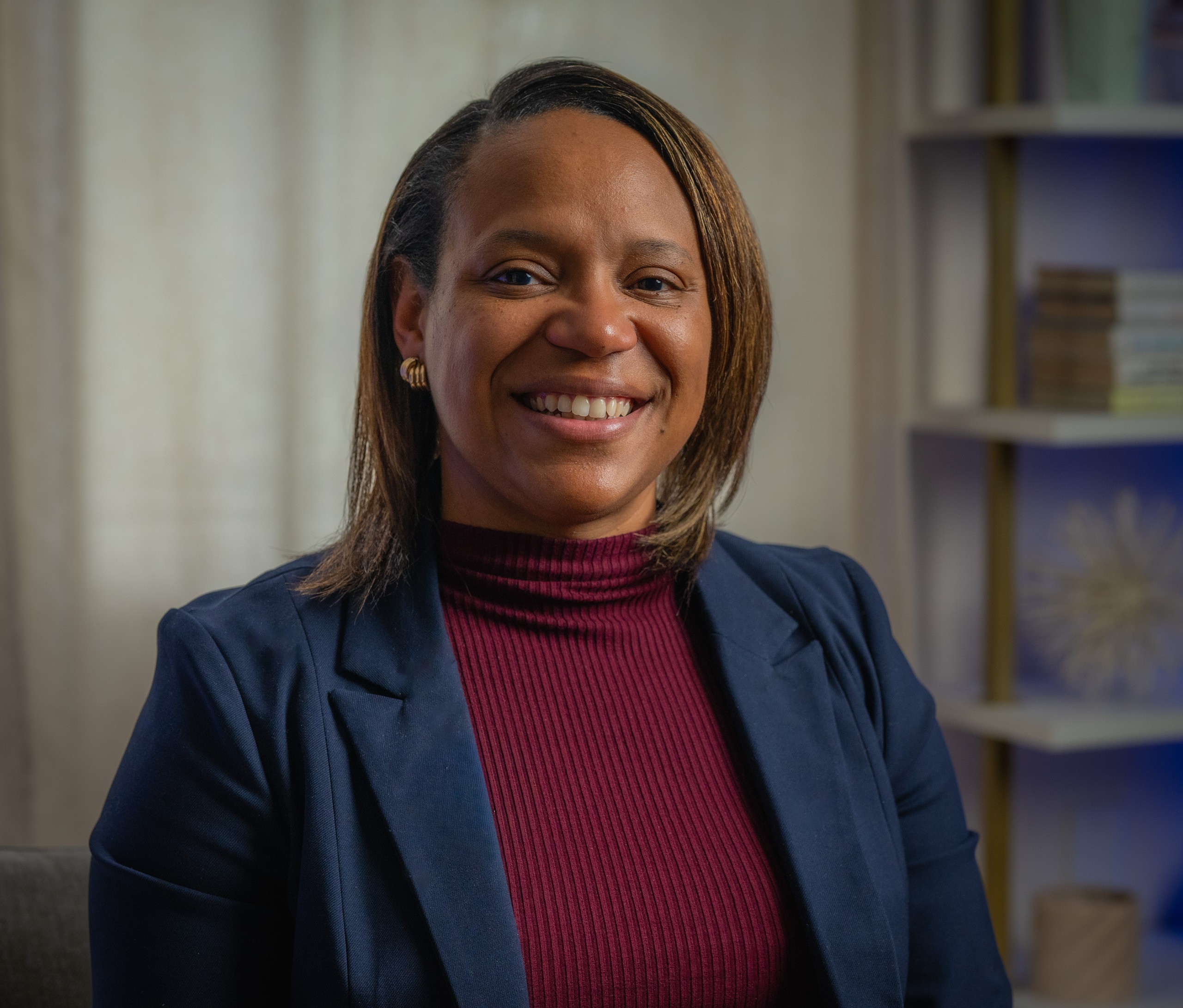 Headshot of LaShaundra Cordier wearing a blue jacket with a maroon top and smiling.